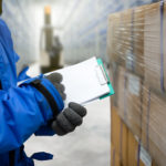 Closeup shooting hand of worker with clipboard checking goods in freezing room or warehouse